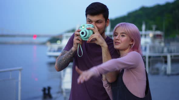 Happy Girlfriend Pointing Away Smiling As Talented Boyfriend Taking Photos with Camera on Urban alt