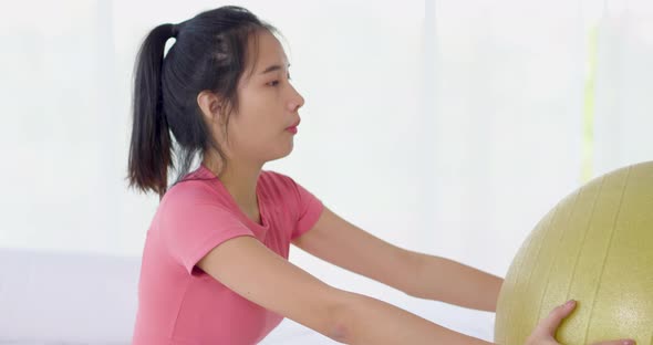 Asian woman squat with yoga ball for muscle workout weight training and yoga exercise at home alt