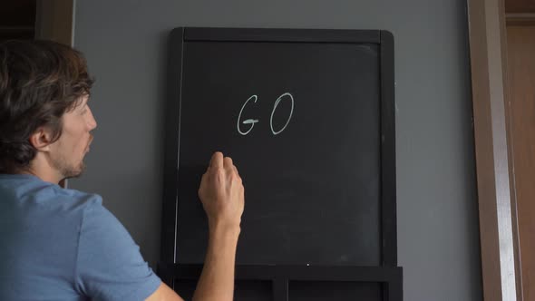 Closeup Shot of a Young Mn That Is Drawing a ' Go Vegan' Message on a Chalkboard alt