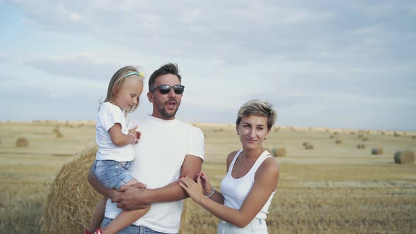 Portrait of Happy Parents with Daughter on Hands Having Talk and Smile alt