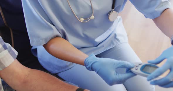 Video of hands of biracial female doctor checking glucose level to caucasian senior man alt