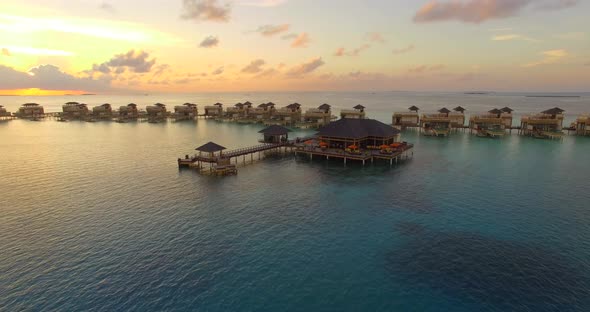 Aerial drone view sunset scenic tropical island, resort hotel with overwater bungalows, Maldives. alt
