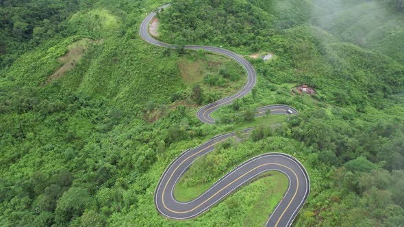 Aerial view of mountain road through tropical forest in countryside of Asia by drone