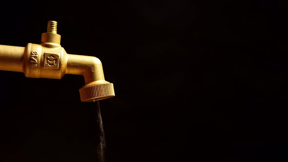 Faucet is dripping and flowing slowly on a black background