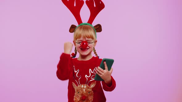 Girl Child in Christmas Deer Antlers Looking Smartphone Display Sincerely Rejoicing Win Success Luck alt