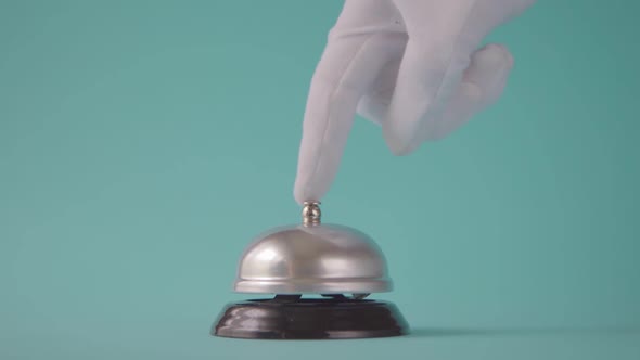 Hand Ringing in Service Bell on a Blue Background