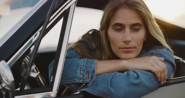 Beautiful woman in a vintage car at sunset alt