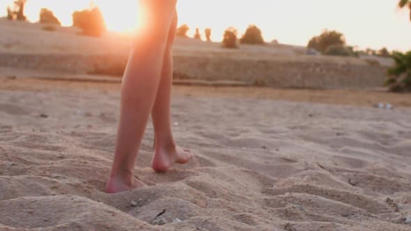 Barefooted Woman is Walking on the Sea Sand Beach at Sunset Legs Closeup alt