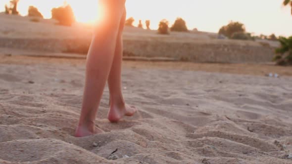 Barefooted Woman is Walking on the Sea Sand Beach at Sunset Legs Closeup