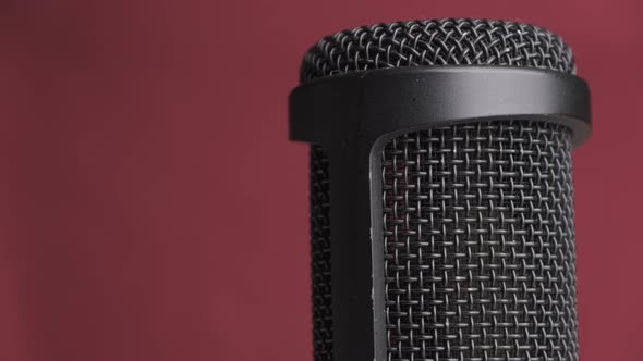 Studio Condenser Microphone Rotates on Red Background with Place for Text alt