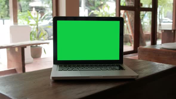 Green screen laptop computer set up for work on wooden desk, Chroma key, Alpha channel.