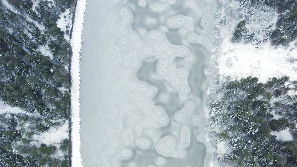 Aerial View at Frozen Lake in the Middle of Winter Forest