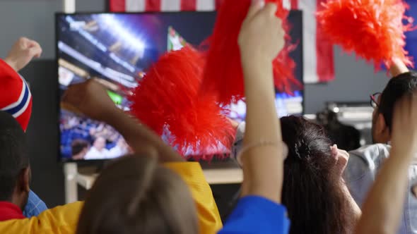 Fans with pom-poms watching match at home