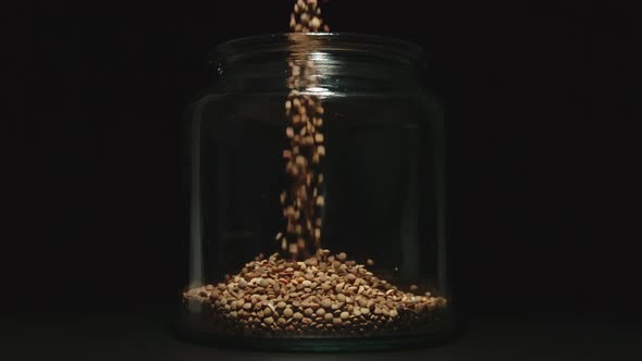 SLOW MOTION: Brown Lentils Grains Pouring Into A Glass Jar  alt