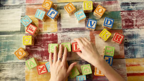 Top View of the Desktop, Women's Hands Add the Word "SALE" From Wooden Cubes