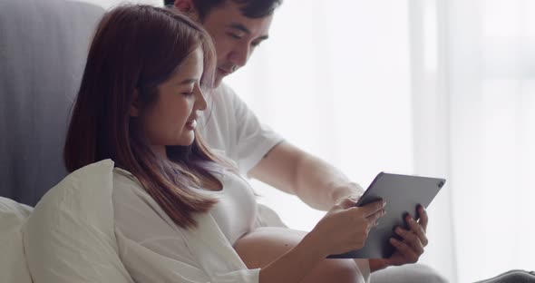 Happy caucasian husband with a pregnant wife looking ultrasound photo of her newborn baby.