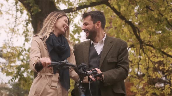 Handsome young couple in the autumn park with electrical bicycle