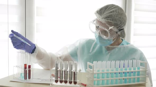 Blood Test for Covid-19 in the Laboratory. Female Laboratory Assistant Working with the Dispenser. alt