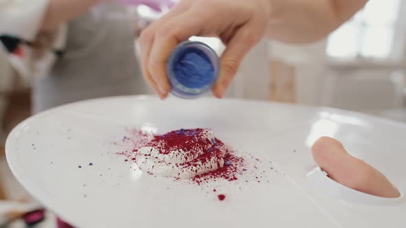 The Artist's Hand Pours a Colored Patch on a Palette with Oil Paint