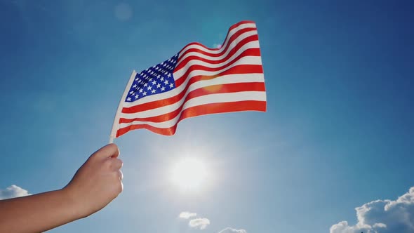 American Flag Against the Backdrop of a Serene Blue Sky and Sun alt