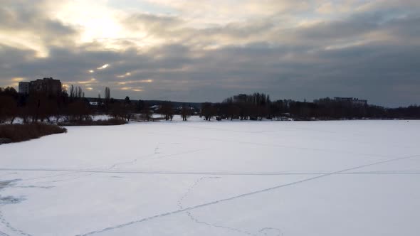 Aerial flying up on frozen wintery river in snow