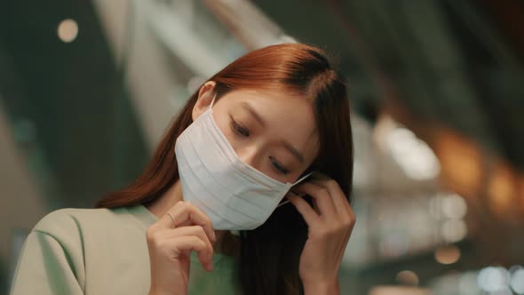 Portrait of Young Attractive Asian Woman wearing a medical face mask sits in a cafe.