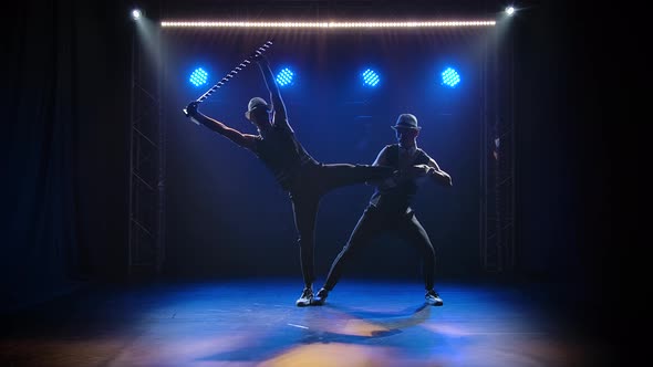 Group of Male Gymnasts Perform Acrobatic Stunts on Balancing. Silhouettes of Two Men on a Black alt