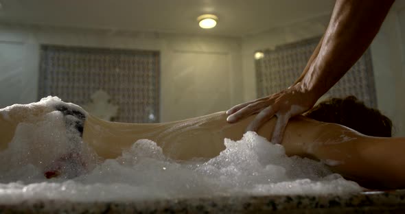 A Woman Lies in a Turkish Bath-in a Hamam on a Huge Table, a Man Poured Foam All Over Her, Massages alt