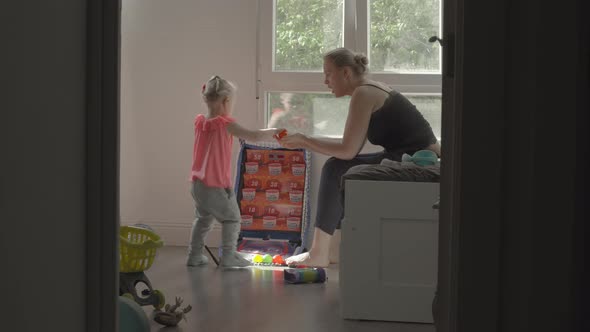 Playful little girl with mum at home alt