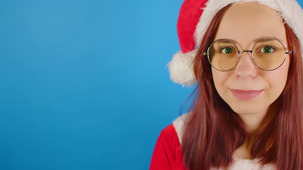Female in christmas hat, eyeglasses looking at camera and smiling alt