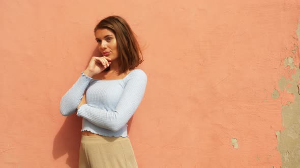 Beautiful Model Posing for the Camera Against Orange Wall alt