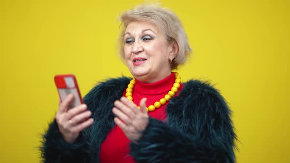 Charming Senior Woman Using Video Chat on Smartphone Smiling alt