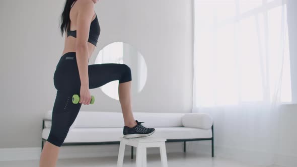 A Young Brunette Woman Performs Concentrated Pacing on a Chair in a Bright Interior Apartment alt