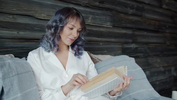 Slow Motion of Beautiful Young Lady Wearing Pajamas Reading Book in Bed alt
