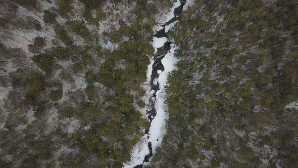 Drone flying high above snowy mountain river in winter alt