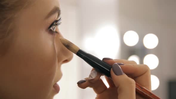 A professional makeup artist puts on eye shadow