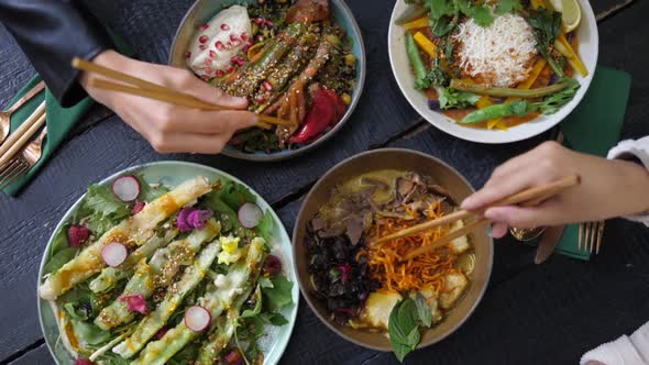 Top View of People Eating Their Healthy Vegan Meals with Chopsticks. Bowls Full of Colorful alt