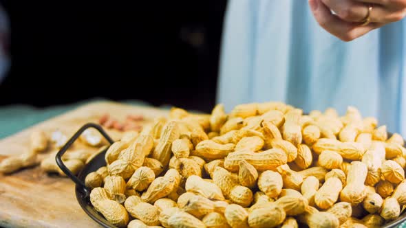 The Woman Analyzes the Quality of Peanuts with Bark alt