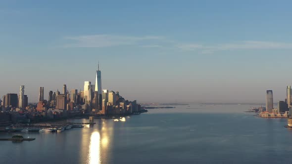 An aerial view of lower Manhattan and New Jersey from over the Hudson River at sunrise. The sun refl alt