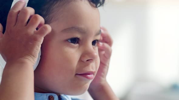 Little African Boy Putting on Headphones and Turning on Player