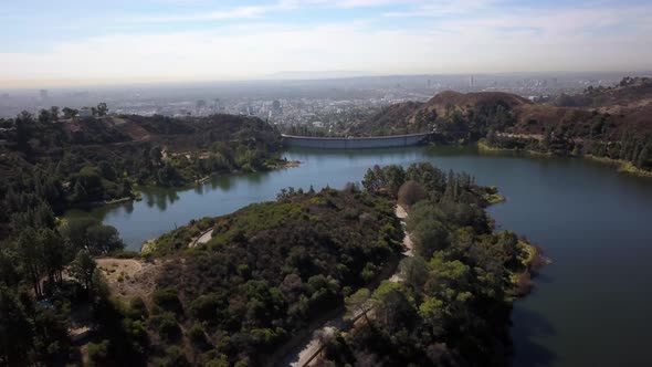 aerial shot circling around hollywood lake and hollywood barrage, with downtown Los Angeles in the b alt