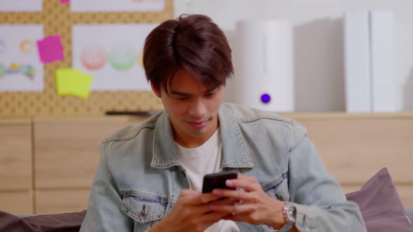 Asian man is smiling and expressing his happy feeling on the cellphone screen alt