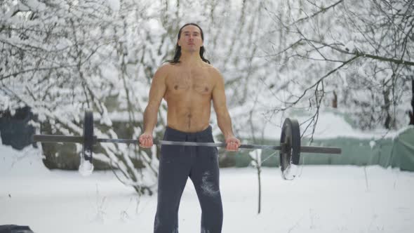 the Guy is an Athlete with Long Black Hair and a Naked Torso Trains in Weightlifting alt