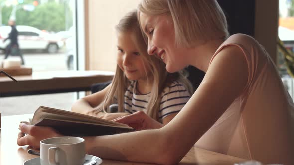 Waiter Gives Some Beverage To the Little Girl at the Cafe alt