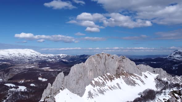 Aerial drone view of difficult access mountain peak for climbers during a winter sunny day alt
