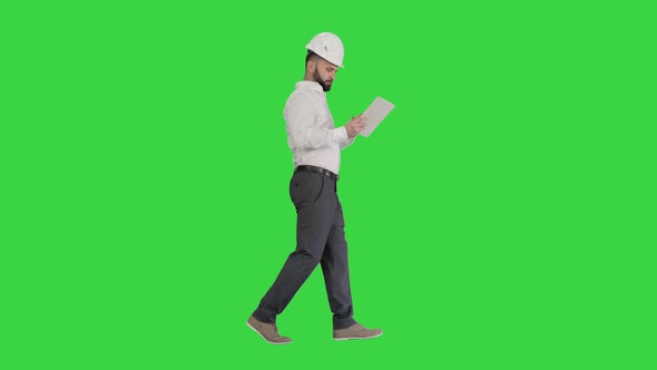 Construction Specialist Using a Tablet Computer While Walking on a Green Screen, Chroma Key. alt