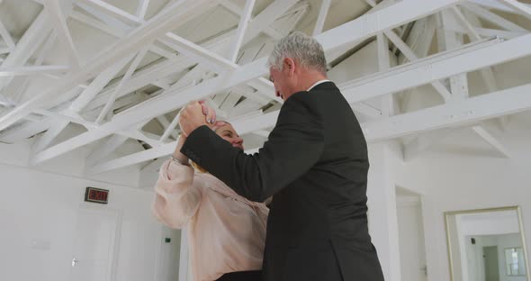 Caucasian senior couple spending time together dancing in a ballroom alt
