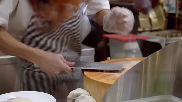 Chef Takes the Fried Chicken and Chops It with a Cleaver on Wooden Board alt