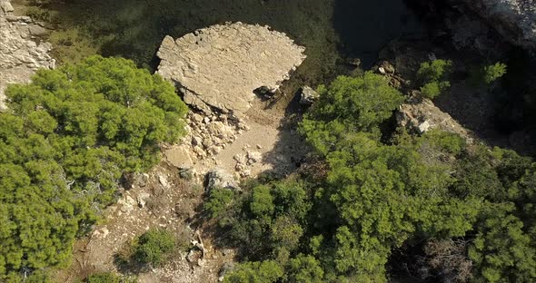 Aerial birds eye view of a small lake surrounded by trees and ancient ruins alt