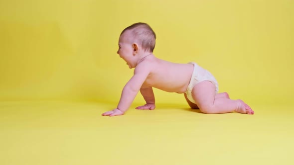 Happy toddler baby plays laughing on studio yellow background